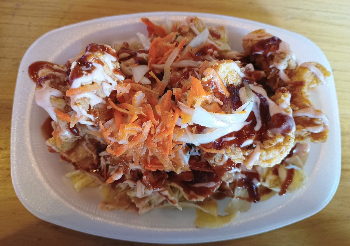 Pollo chuco: fried chicken over tajadas with shredded vegetables and sauces