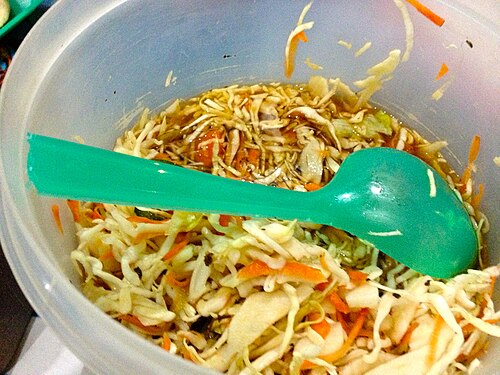 Shredded cabbage and carrot curtido with a serving ladle